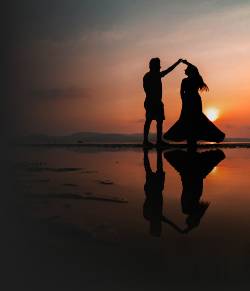 Couple silhouetted against a warm sunset sky